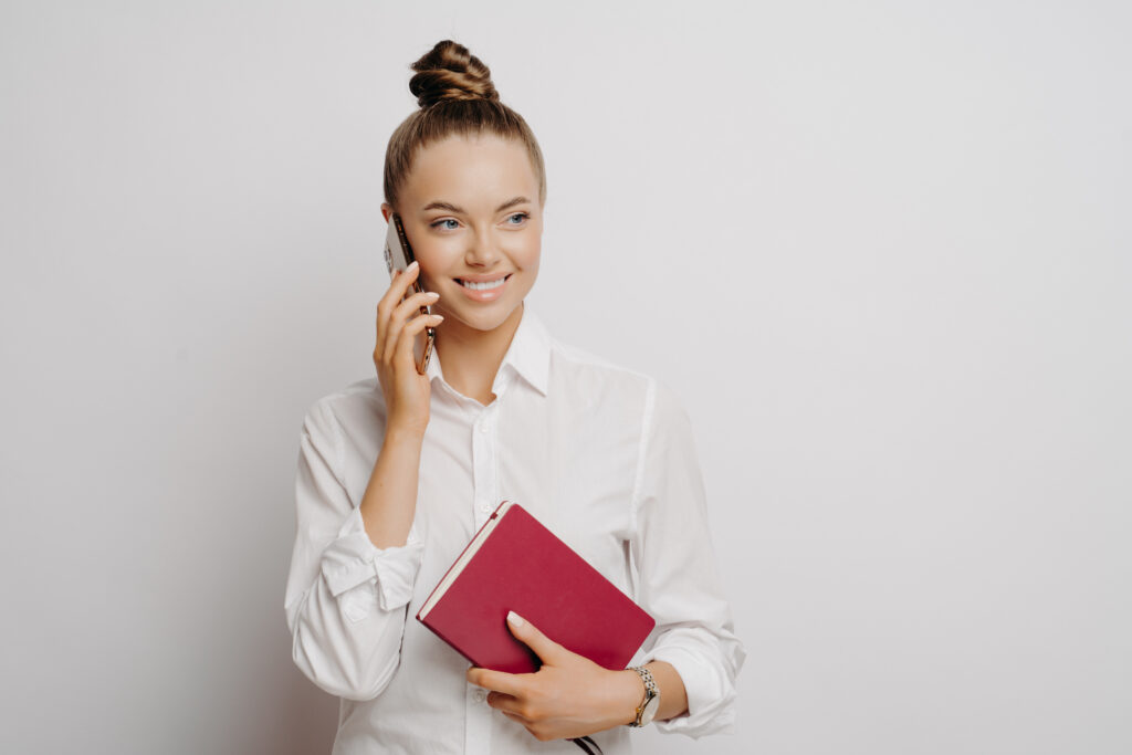 happy business woman in white shirt with phone and notebook